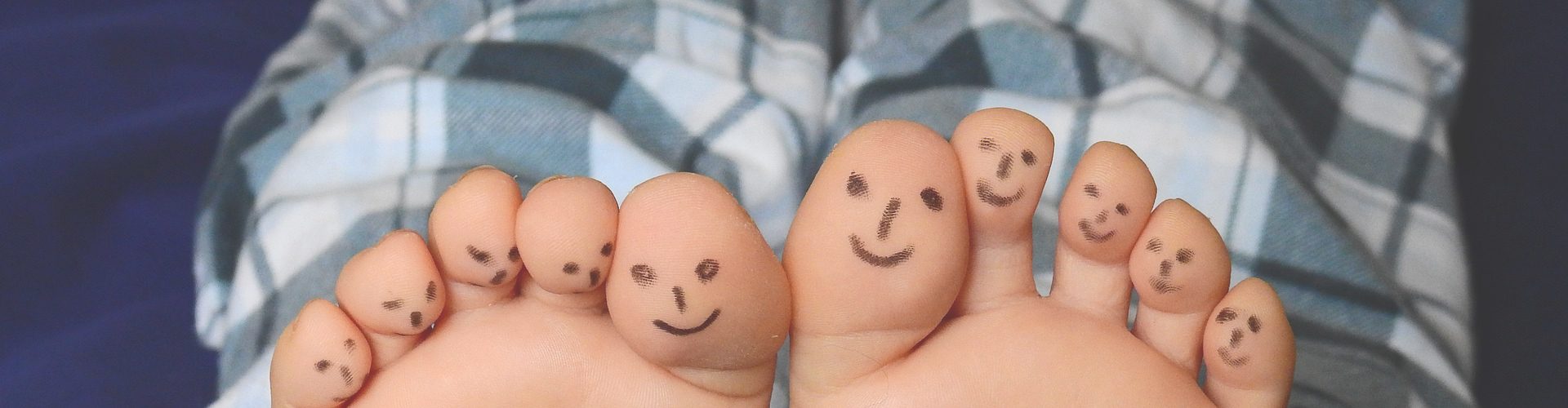 PJ Days - smiley faces drawn on the bottom of toes, legs wearing pjs visible above.