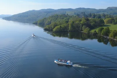 Two boats sail past Wray Castle on the western shore of Lake Windermere.