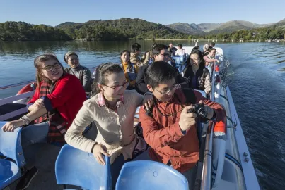 A tour group on the top deck of cruise photographing the mountain views.