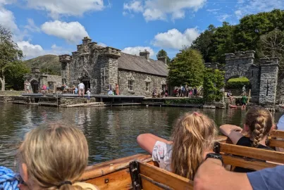 Children seated on board a boat with a Visctorian boathouse at Fell Foot Park.