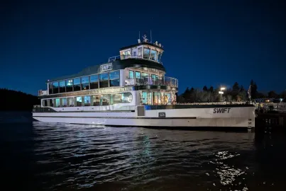 MV Swift in Bowness Bay at dusk with lights on.