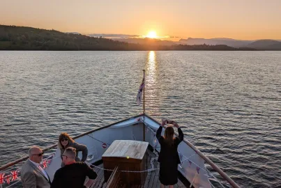 A customer takes a photograph of the sun setting behind the Lakeland fells.