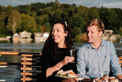 A couple on board the Summer Evening Buffet Cruise with a glass of champagne and a meal.