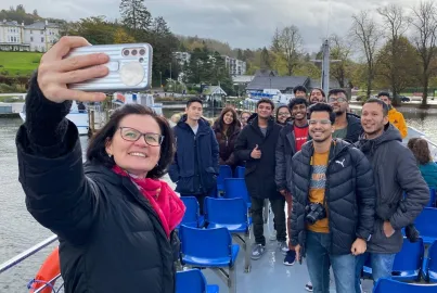 A group of students and their tutor take a selfie on board a cruise from Bowness Pier.