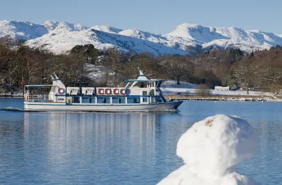 Miss Lakeland II travelling past a snowman on the shore