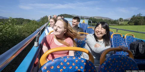 A group of passengers on top an open top bus in The Lake District