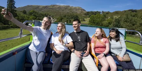 A group of people on the top deck of an open-top bus
