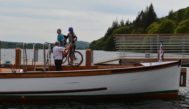 Two cyclists bringing bikes on board the Cross Lakes service.