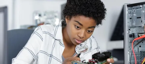 An ICT technician working in an office mending a computer.