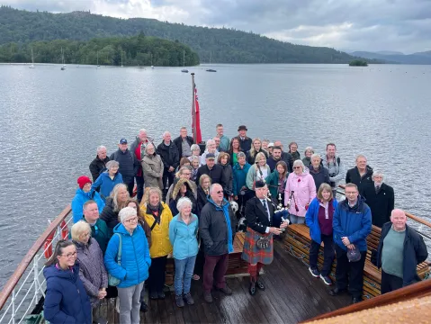 Piper Richard Cowie plays his D-Day tribute on the deck of Windermere Lake Cruises' vessel MV Teal surrounded by staff and members of the public.