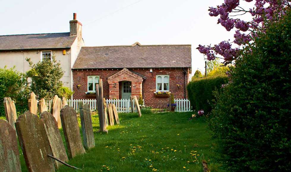 A converted schoolhouse next to a churchyard
