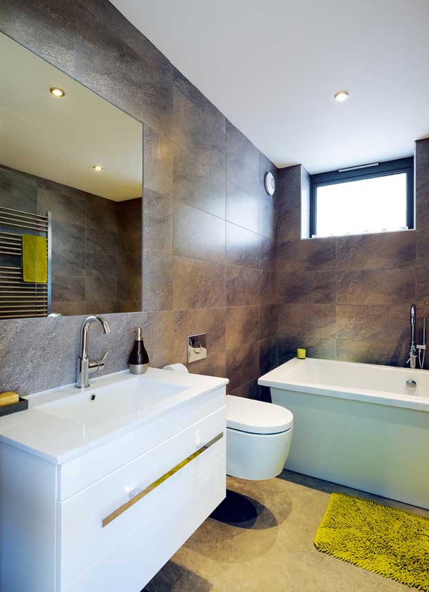 A contemporary bathroom with large, dark tiling