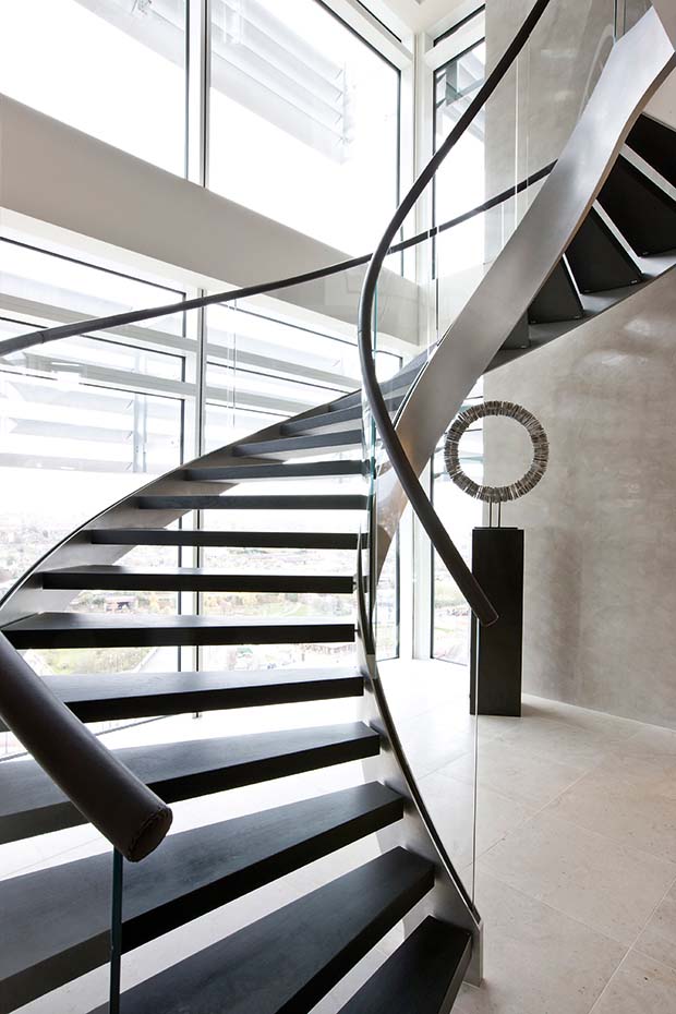 Helical staircase from Bisca with glass balustrades and brown leather handrail