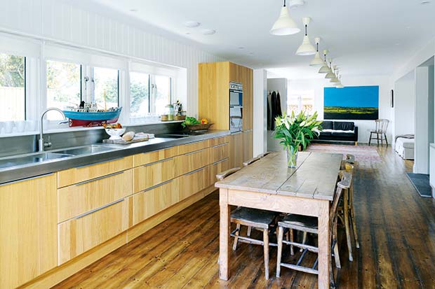 A kitchen in an open plan home with stainless steel worktop and wooden finishes