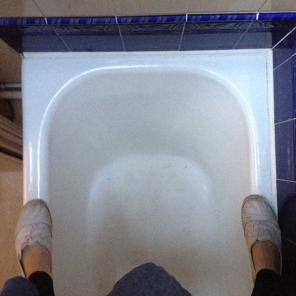 Lindsey standing on enamelled bath to look in loft