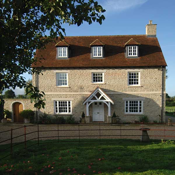 Natural stone, reclaimed clay roof tiles and timber sashes for a new farmhouse