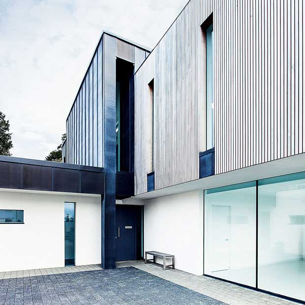 Low-maintenance exterior finish of render, zinc and cedar