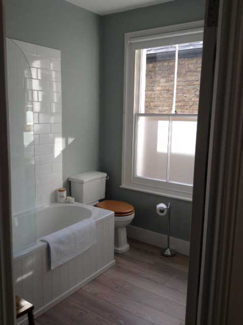 blue-green bathroom with sash window and metro tiles