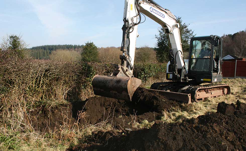 Digger removing topsoil on building site