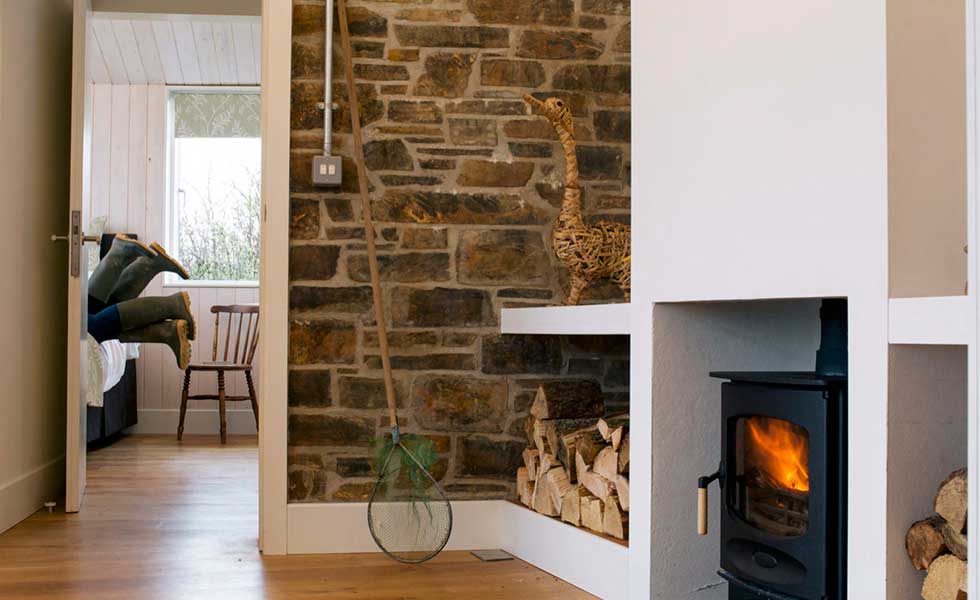 exposed brick wall in lounge space with log burner
