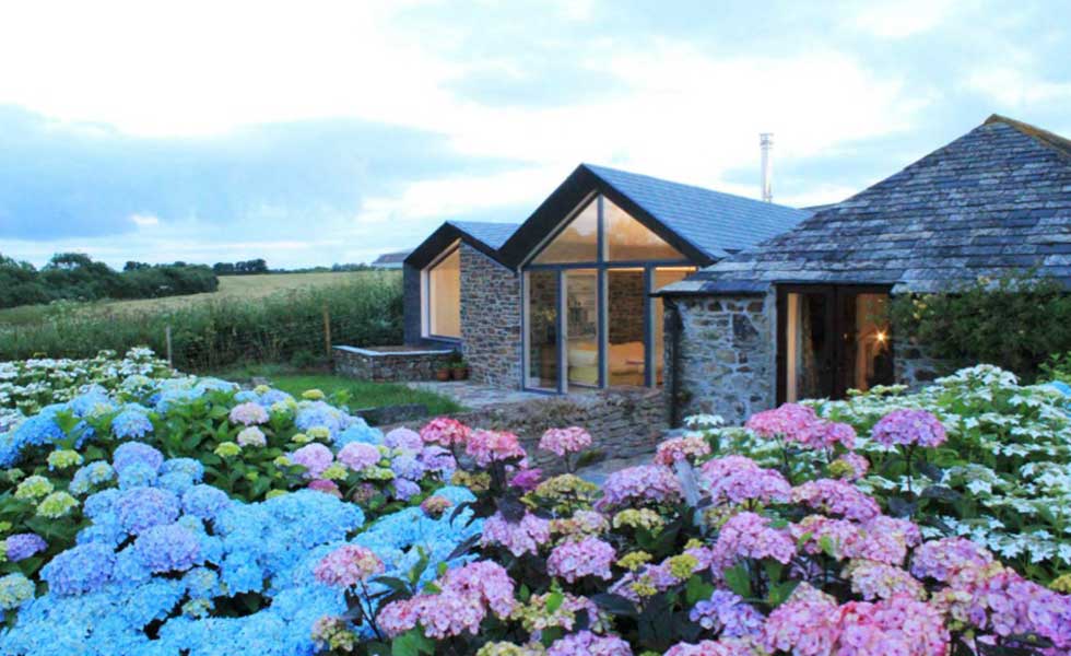 stone cottage with glass front and floral garden