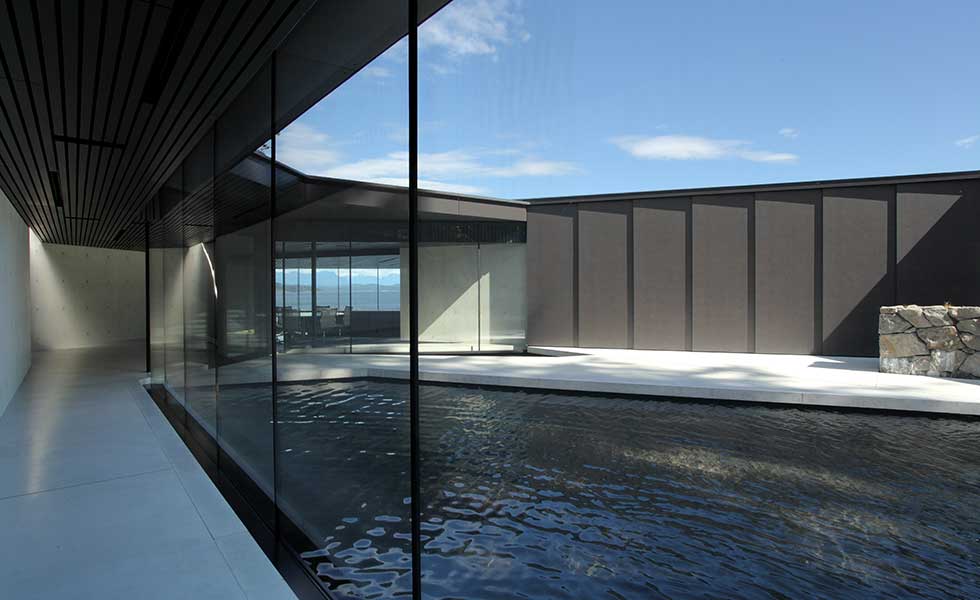 courtyard of glass and dark wood fronted contemporary home with central pool