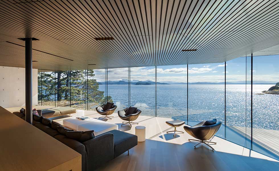 living room view of modern home with glass windows overlooking lake