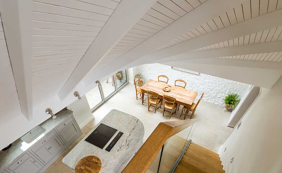 shot from above of open plan kitchen with marble topped island and wooden table
