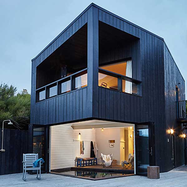 square contemporary home with black panels, balcony and sliding corner door