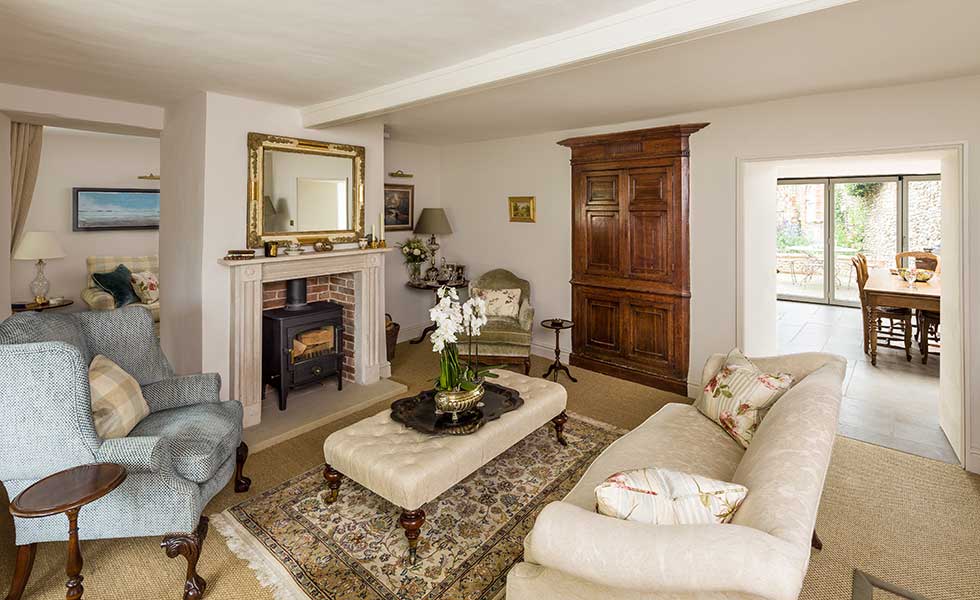 country feel living room with collection os fabric sofas a large central footstool and log burner in original open fire