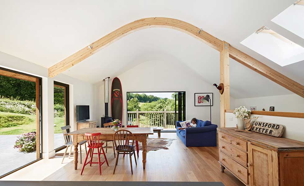 living room with white curved ceiling and wooden beams and collection of mismatching wooden furniture