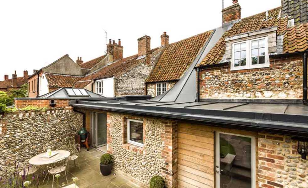garden shot of house that uses multiple stones with a small patio and sliding doors