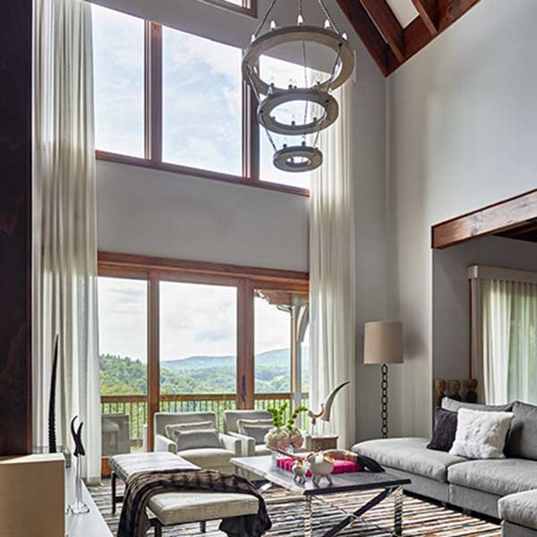 living space with high ceilings , glass doors overlooking countryside and hanging white light fixture