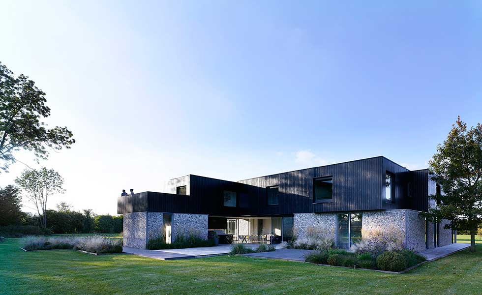 view of contemporary boxy shaped home with wooden paneling and stone finish also featuring a balcony