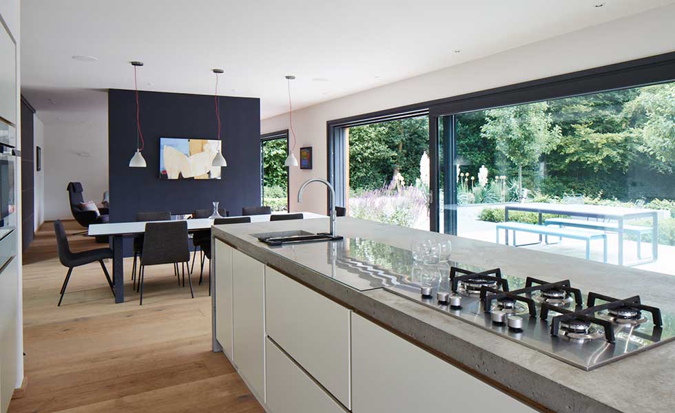open plan living space with large glass sliding doors, wooden flooring and dark feature wall