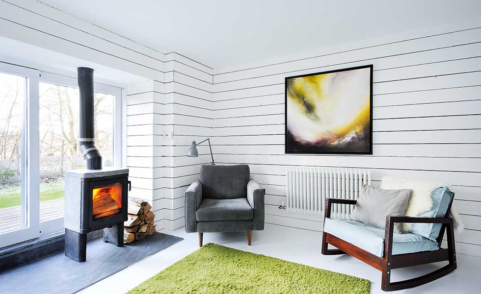 scandi style living room with white panelled walls, a green rug and small log burner
