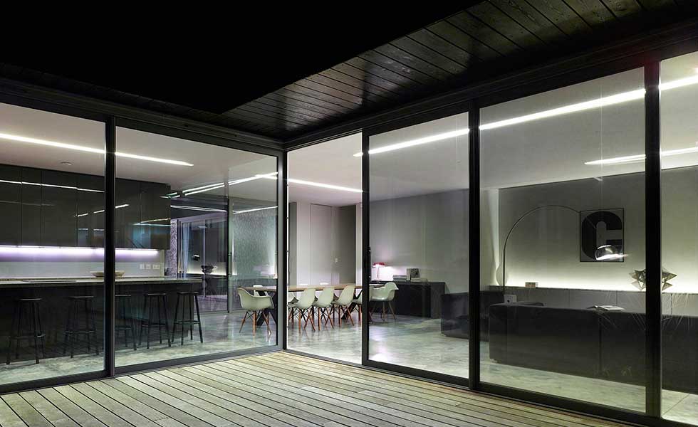 sliding glass doors looking into dark interior of a contemporary open plan living space