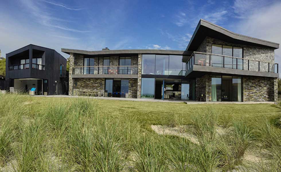view of modern beachside home in sand dunes