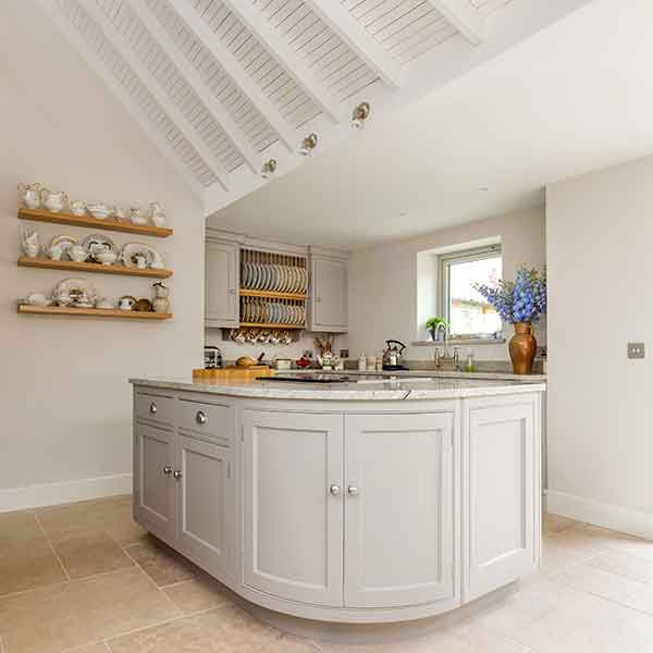 curved kitchen island with panelled ceiling and marble table surfaces