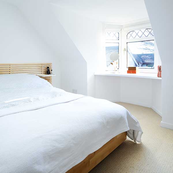 white bedroom with white bedding and wooden bed frame
