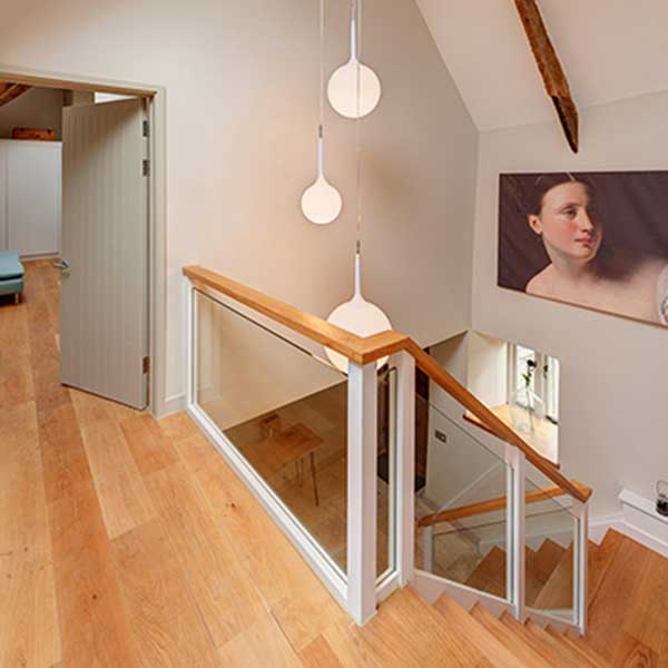 white hallway with wooden staircase and hanging pendant lampshades