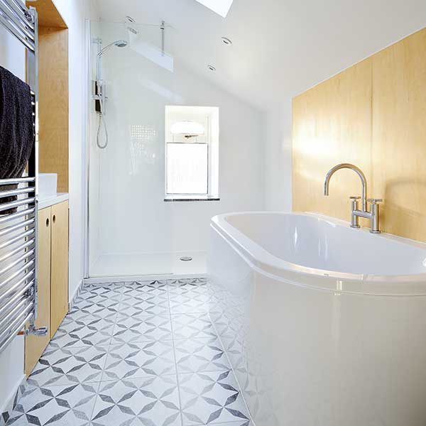 white bathroom with wooden panelling, white and grey patterned tiles and freestanding bath