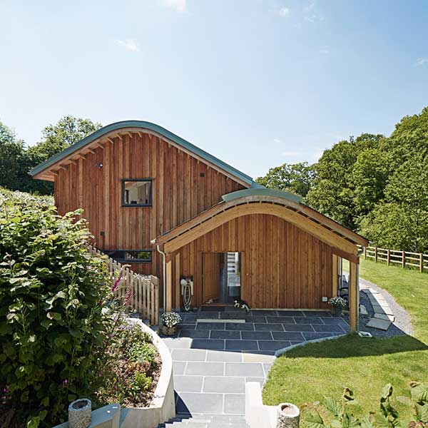 curved roof wooden panelled home in open green space