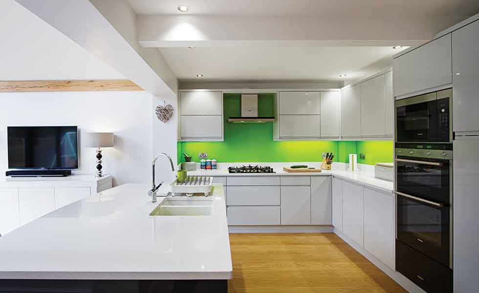 Green splash backs contrast against the white gloss kitchen units in this oak frame extension
