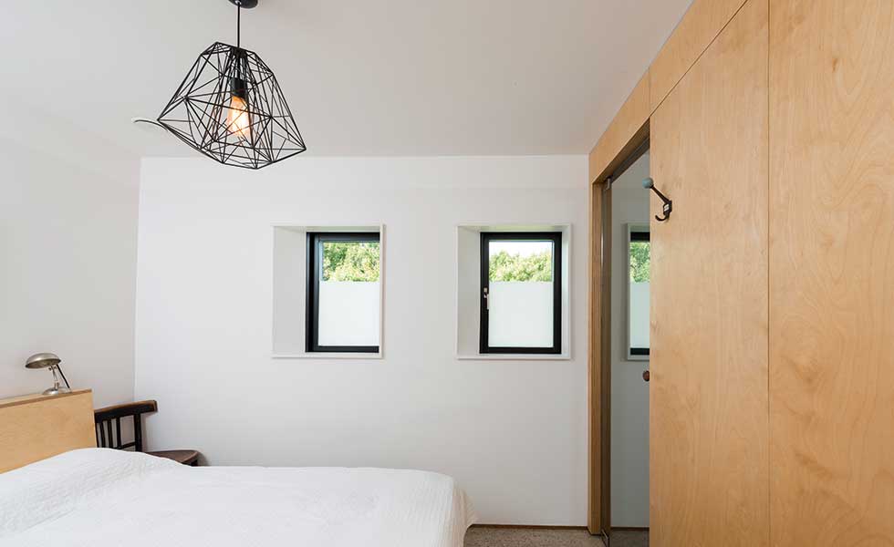 white minimalist bedroom with a plywood clad bathroom area