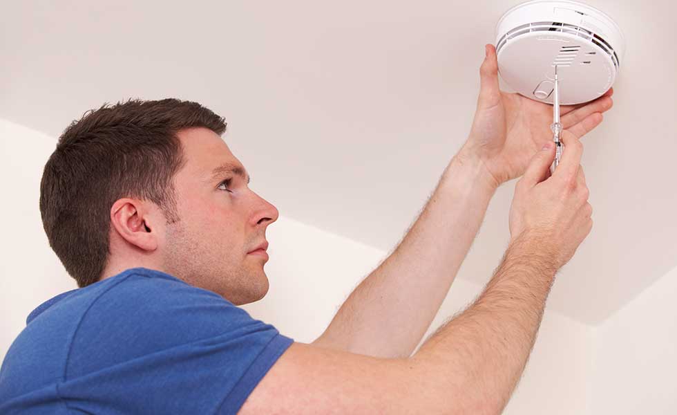 man fitting a safety alarm such as a smoke alarm