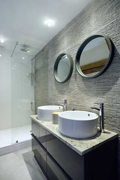 En suite shower room with twin basins and stone tiled walls