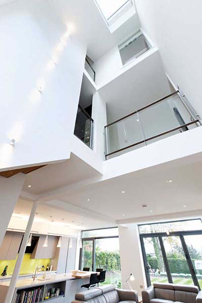 A dramatic triple-height void in this contemporary self build leads the eye upwards thanks to a rooflight positioned at the apex. Galleried sections with glazed balustrades at first and second floor level allow each part of the home to enjoy views up and down the void.