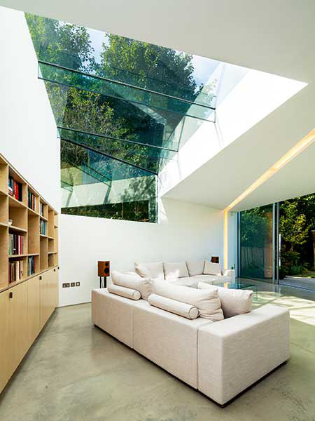 In this extension project, the tall ceiling has been punctured with structural frameless glazing which moves down the rear wall. Combined with the design of the glazing sitting above the ceiling height to one side of the room, the homeowners benefit from an open air feel.