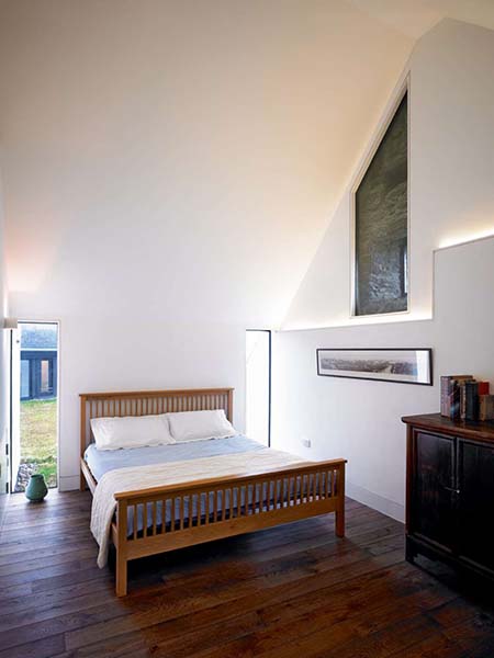 The steeply sloping pitch of the ceiling in this bedroom creates an almost triangular shaped space